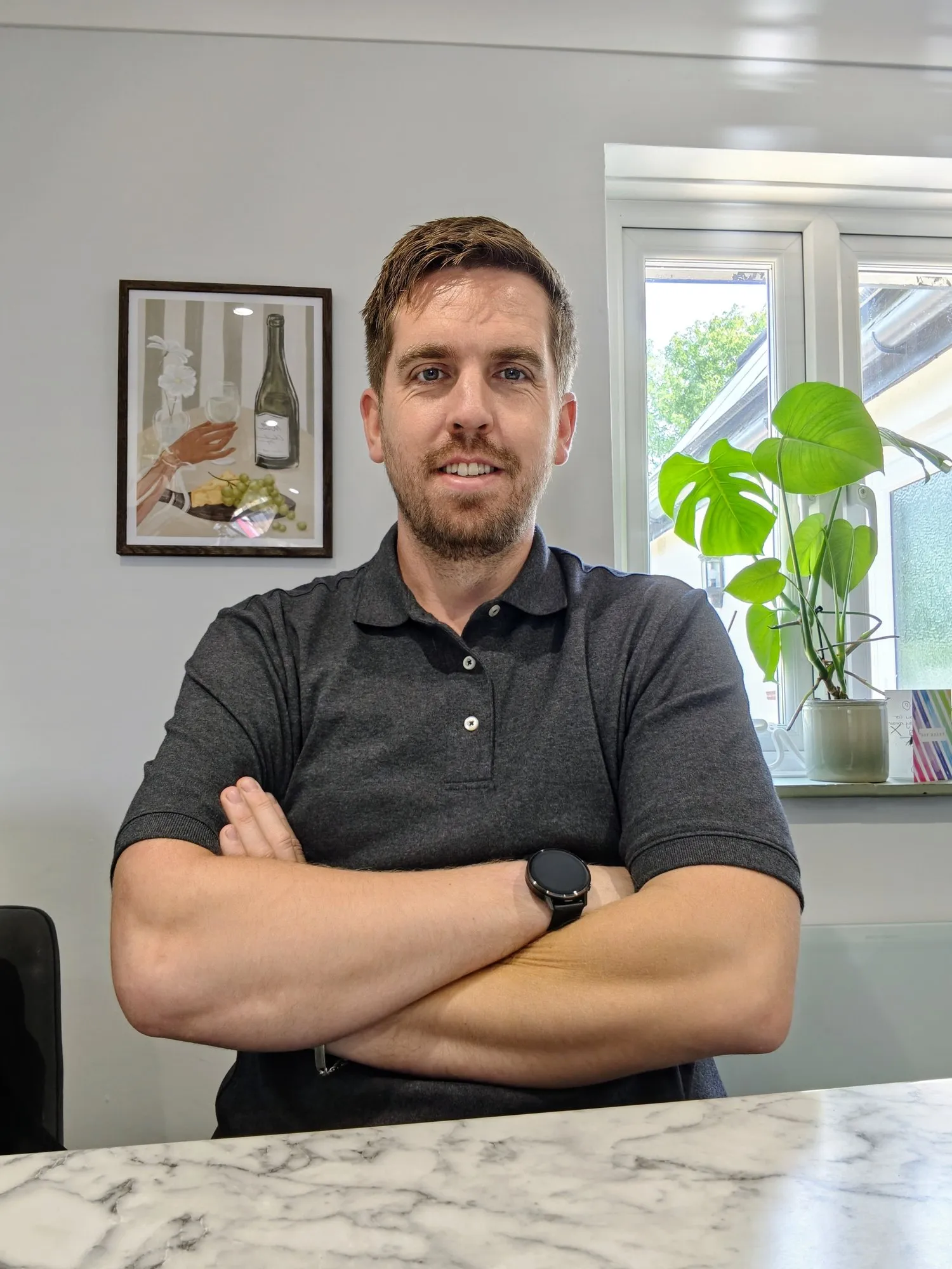 Dom Mills, founder of Dominion TechOps, sitting at a kitchen worktop with his arms folded